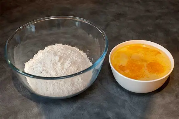Bowls side by side of the dry and wet ingredients for the waffle batter