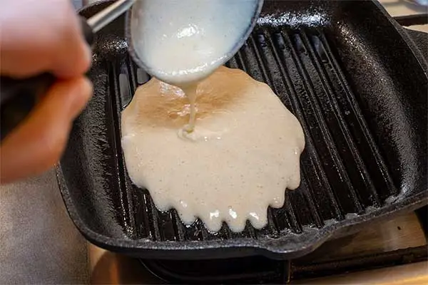 Pouring-three-quarters-of-a-cup-of-waffle-batter-into-the-grill-pan