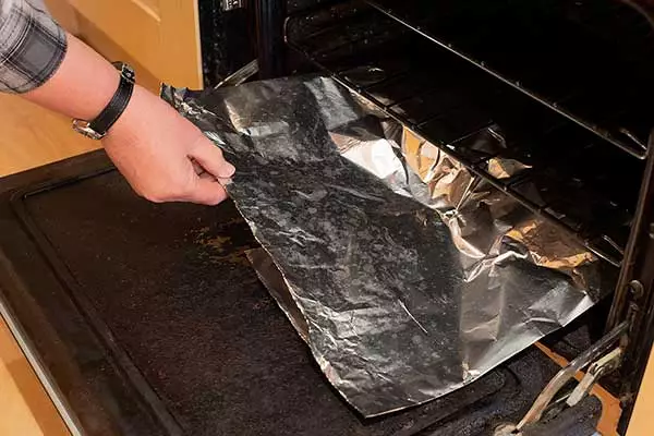 Covering the base of the oven with aluminium foil