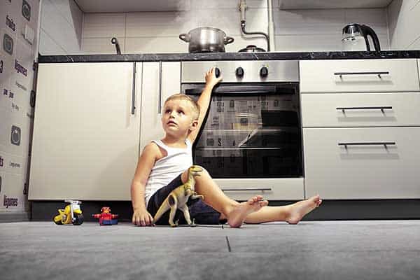 Child in danger beneath a pan on a stovetop