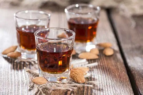 three shots of Amaretto on a rustic table top