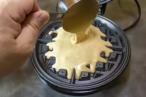 Pouring batter into waffle maker