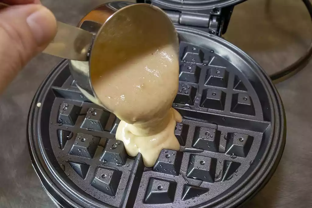 Pouring waffle batter into an electric waffle maker